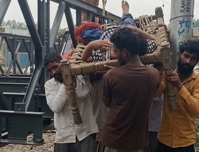 Bajpur: बेरिया रोड बंद होने पर घायल महिला को चारपाई पर लिटाकर  निकाला 